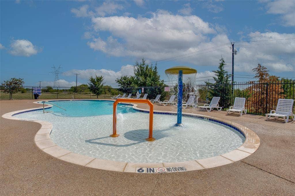540 S Heights Drive, Crowley, TX 76036 Swimming pool featuring a zero-entry design, water play structure, and concrete decking enclosed by perimeter fencing