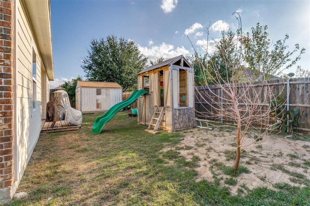 540 S Heights Drive, Crowley, TX 76036 Rear yard featuring a wood fence enclosure, detached storage structure, and brick exterior wall