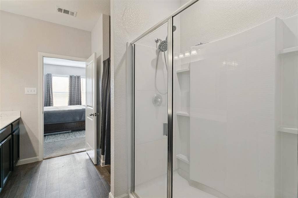 540 S Heights Drive, Crowley, TX 76036 Walk-in shower with white surround, glass enclosure, and multi-setting shower head, paired with dark wood-finish cabinetry and a light-toned countertop