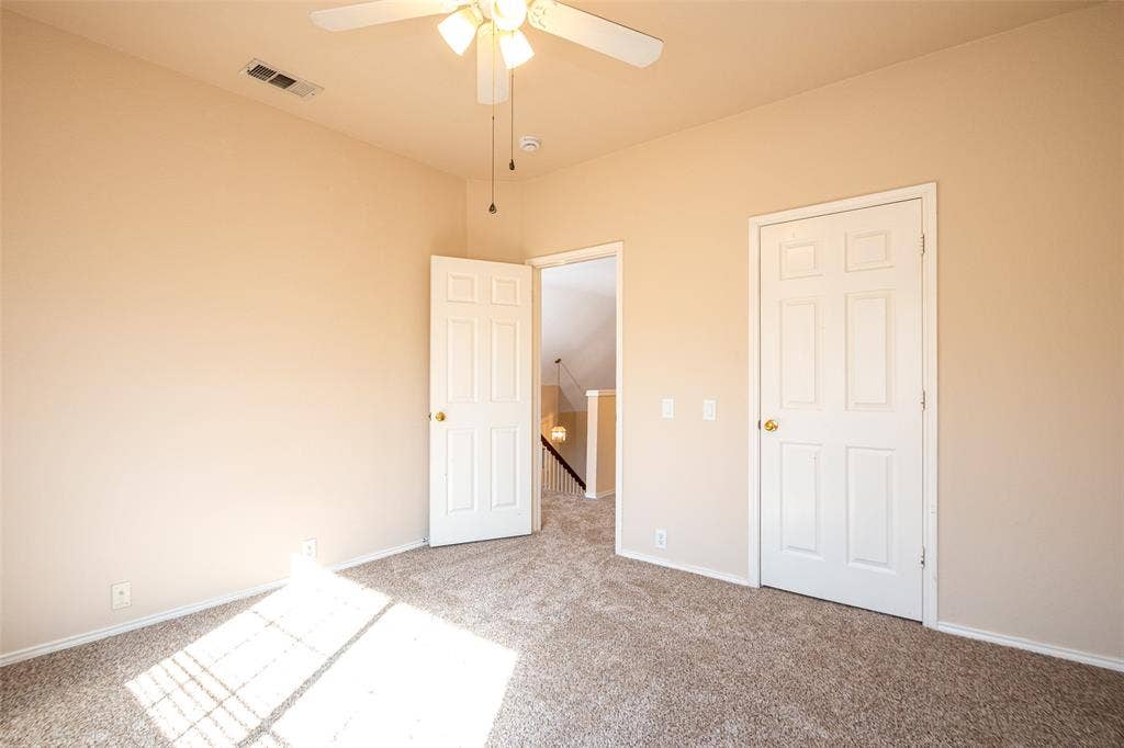 Textured carpeting, light neutral wall paint, overhead ceiling fan with lighting, white interior doors, and white trim throughout