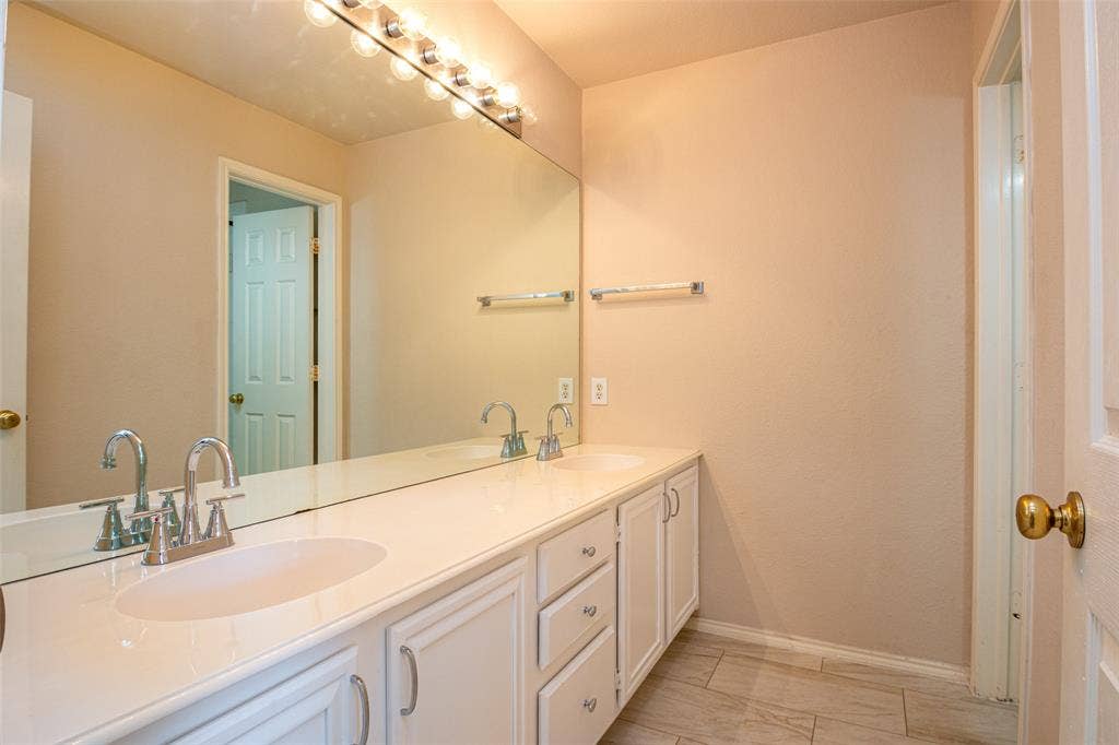 Dual vanity with integrated sinks, polished chrome fixtures, extensive countertop space, and white cabinetry