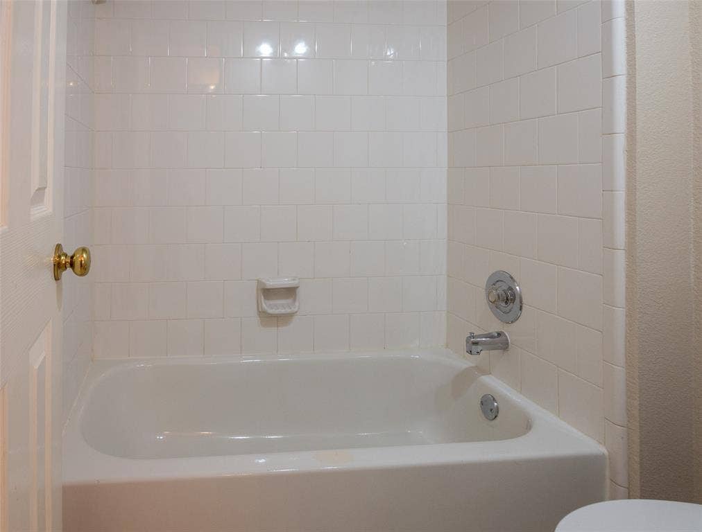 White subway tile surround, built-in bathtub, and chrome fixtures