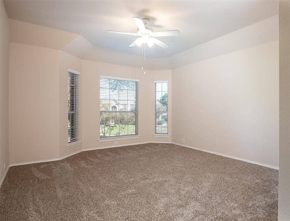 Tray ceiling with a ceiling fan, bay windows with blinds, and wall-to-wall carpeting