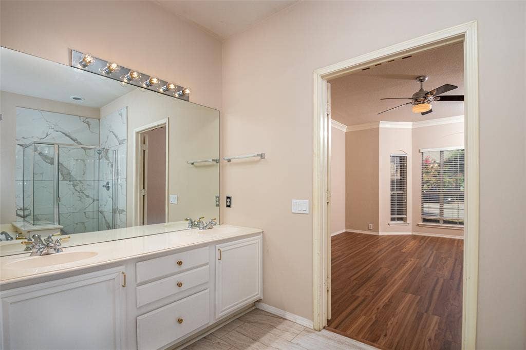 Spacious bathroom vanity with dual sinks and ample storage, large framed mirror, and an updated shower with glass enclosure