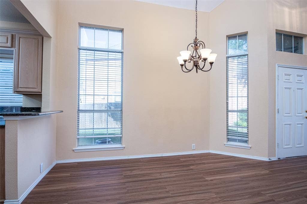 Vaulted ceiling with an iron chandelier, wood-finish flooring, and multiple tall windows