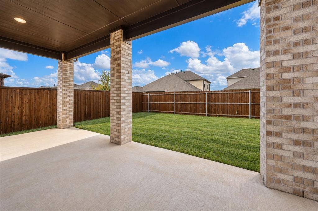 3681 Keechi Creek Drive, Celina, TX 75078 Virtually improved image. Covered patio featuring a concrete floor, recessed ceiling lighting, and brick support columns, opening to a fenced backyard with a lawn
