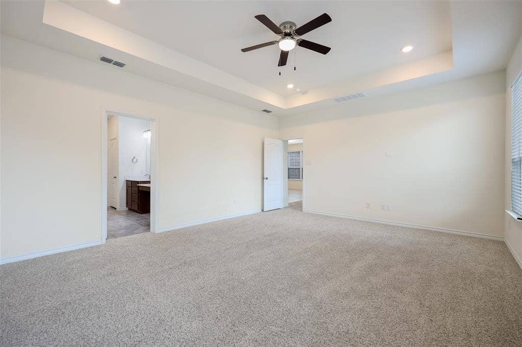 3681 Keechi Creek Drive, Celina, TX 75078 Spacious room featuring a tray ceiling, neutral wall-to-wall carpeting, and a ceiling fan with integrated lighting