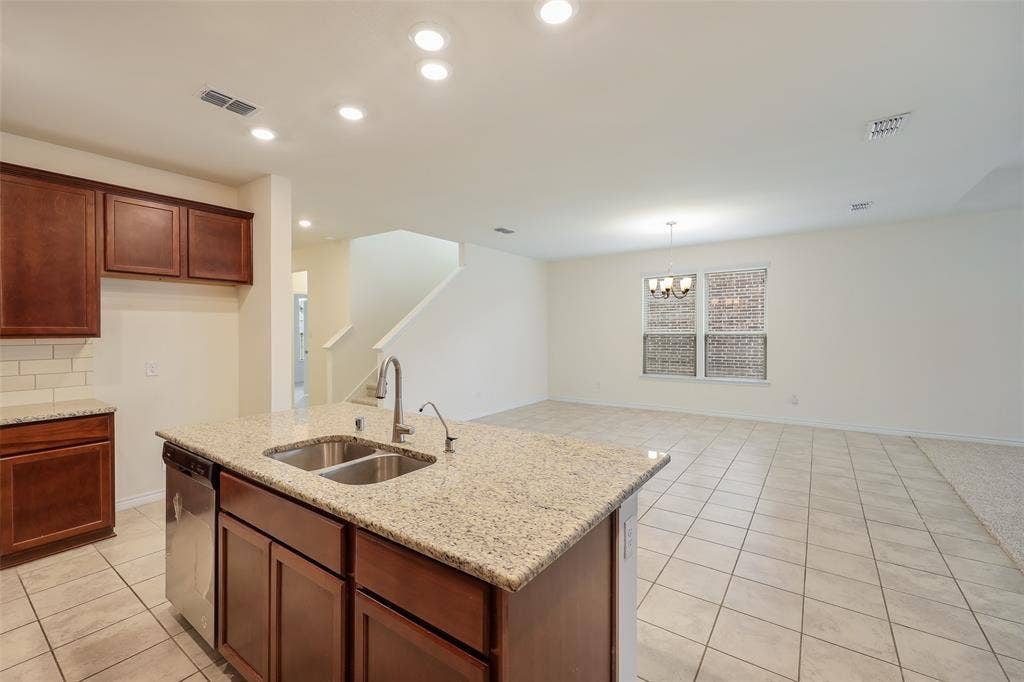 3681 Keechi Creek Drive, Celina, TX 75078 Kitchen featuring a central island with a dual-basin stainless steel sink, stone-finish countertops, recessed lighting, and tile flooring