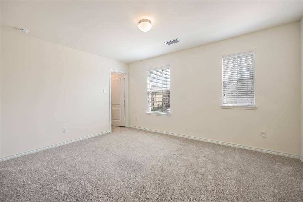3681 Keechi Creek Drive, Celina, TX 75078 Neutral-toned interior space featuring plush carpeting, two windows with horizontal blinds, a ceiling-mounted flush-mount light fixture, and a single-panel interior door