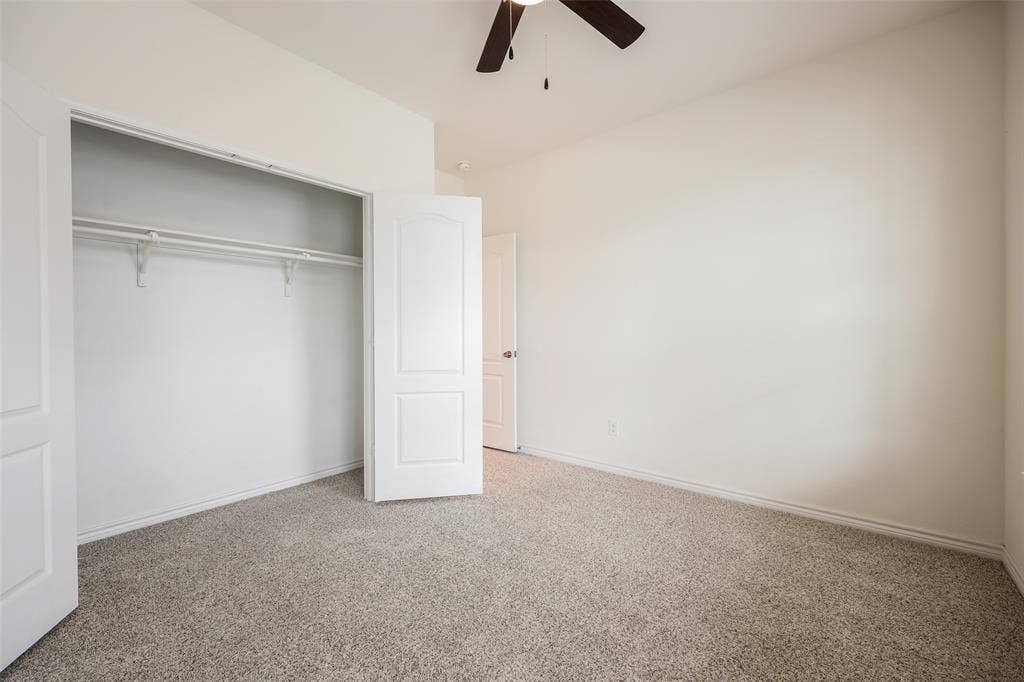 3681 Keechi Creek Drive, Celina, TX 75078 Neutral-toned carpeting, white interior doors with arched paneling, walk-in closet with built-in shelving, and a ceiling-mounted fan with light fixture