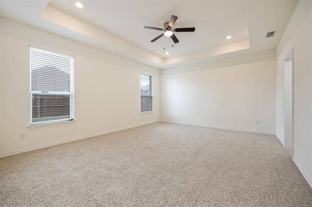 3681 Keechi Creek Drive, Celina, TX 75078 Interior room featuring a tray ceiling, recessed lighting, a ceiling fan, neutral carpeting, and multi-pane windows