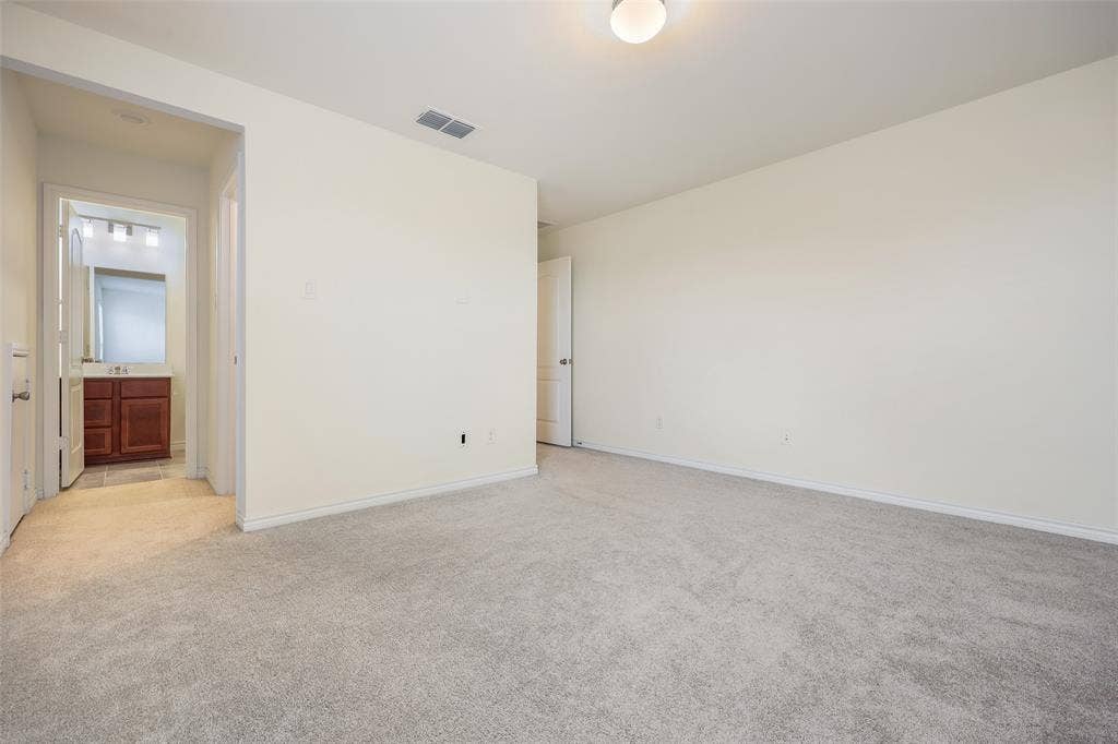3681 Keechi Creek Drive, Celina, TX 75078 Neutral-toned interior space featuring wall-to-wall carpeting, flush-mount ceiling lighting, and a doorway revealing a bathroom with wood-finish cabinetry and a vanity mirror