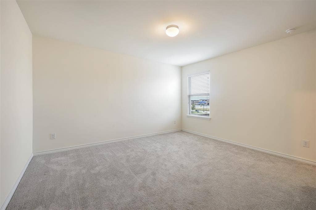 3681 Keechi Creek Drive, Celina, TX 75078 Neutral-toned interior room featuring wall-to-wall carpeting, a single-pane window with integrated blinds, and a flush-mount ceiling light fixture