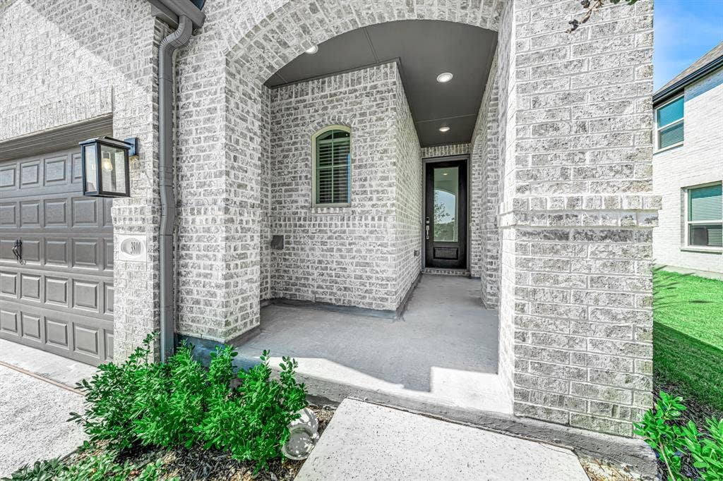 3800 Talisker Boulevard, Sherman, TX 75090 Light brick exterior with an arched entryway, recessed lighting, and a dark paneled garage door