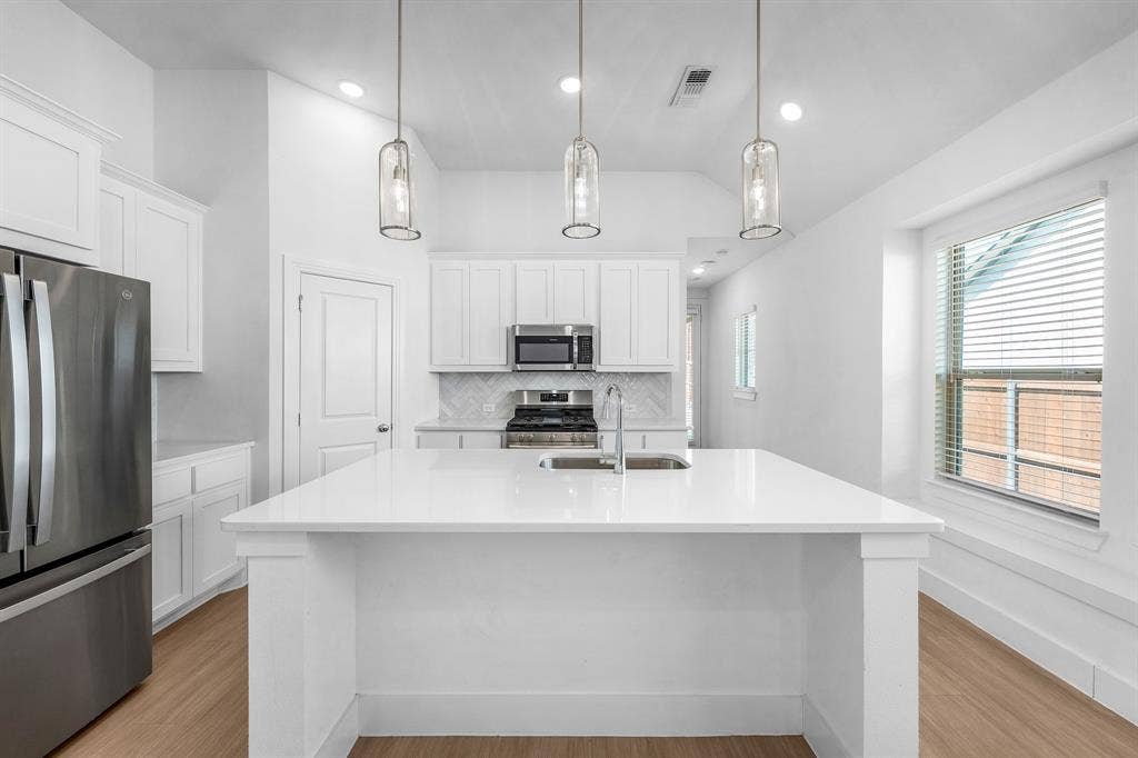 3800 Talisker Boulevard, Sherman, TX 75090 Bright kitchen featuring a center island, recessed lighting, pendant fixtures, stainless steel appliances, and wood-finish flooring