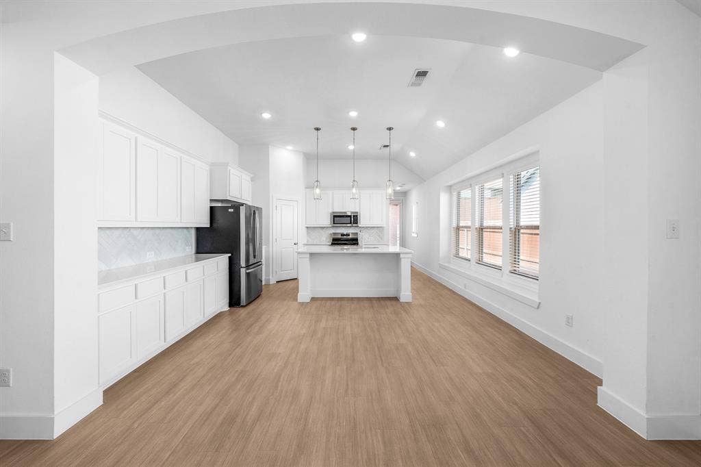 3800 Talisker Boulevard, Sherman, TX 75090 Open-concept living area with wood-finish flooring, white cabinetry, a kitchen island, and recessed lighting