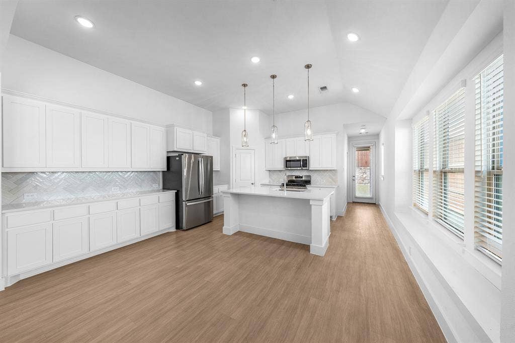3800 Talisker Boulevard, Sherman, TX 75090 Open-concept kitchen with white cabinetry, stainless steel appliances, and wood-finish flooring