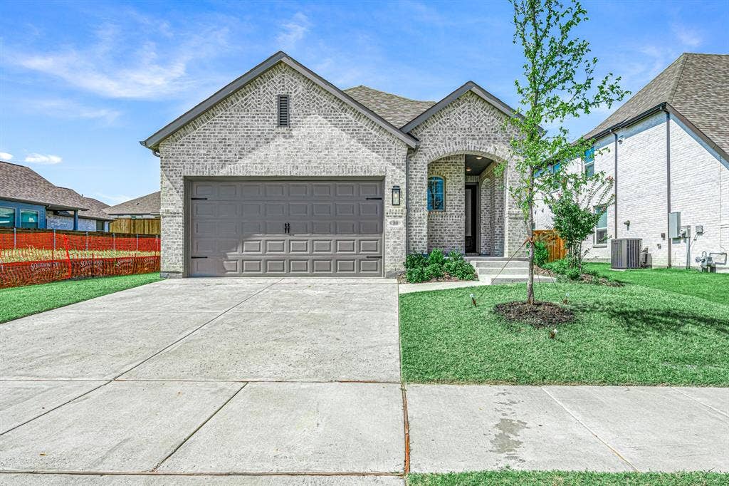 3800 Talisker Boulevard, Sherman, TX 75090 Light-colored brick exterior with an arched entry, attached two-car garage, concrete driveway, and manicured lawn