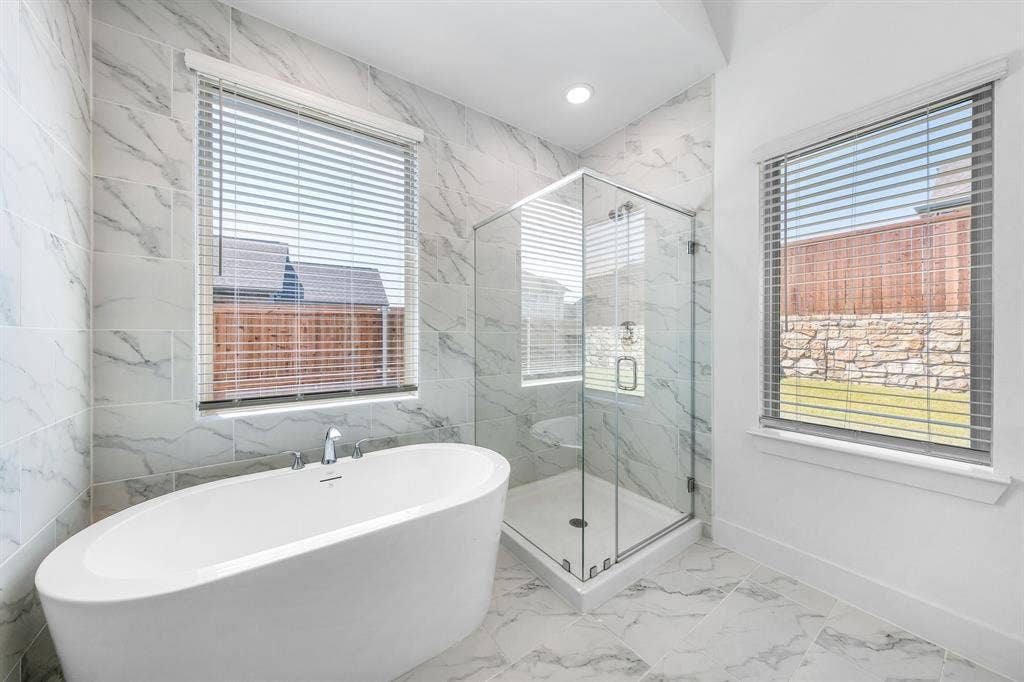 3800 Talisker Boulevard, Sherman, TX 75090 Freestanding oval soaking tub with chrome fixtures, glass-enclosed shower with bench, and large format wall and floor tile