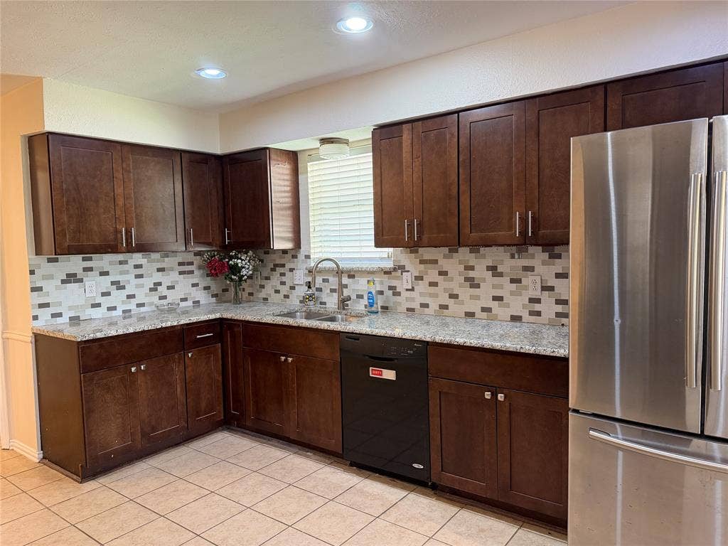 2408 Skiles Drive, Plano, TX 75075 Kitchen featuring dark wood-finish cabinetry, light-toned countertops, a mosaic tile backsplash, stainless steel refrigerator, and recessed lighting