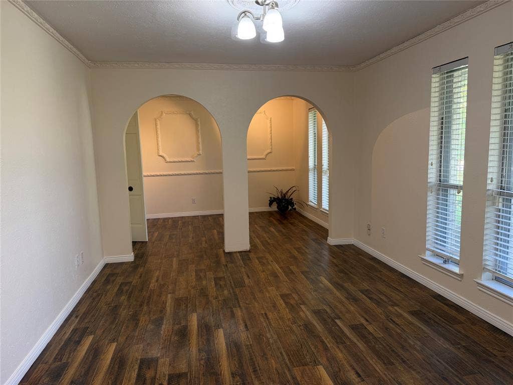 2408 Skiles Drive, Plano, TX 75075 Wood-finish flooring throughout, decorative arched doorways, multiple windows with horizontal blinds, decorative wall molding, and crown molding