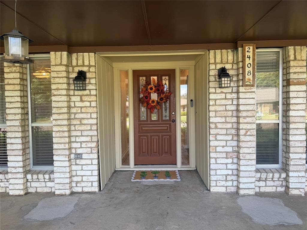 2408 Skiles Drive, Plano, TX 75075 Brick facade with vertical siding accents, decorative entryway with sidelights, and exterior light fixtures