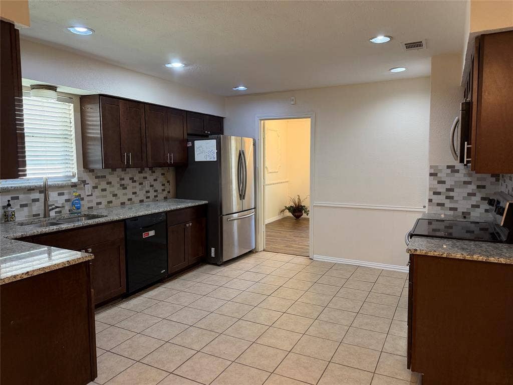 2408 Skiles Drive, Plano, TX 75075 Expansive kitchen featuring dark wood cabinetry, light-colored tile flooring, speckled countertops, a patterned tile backsplash, and recessed lighting