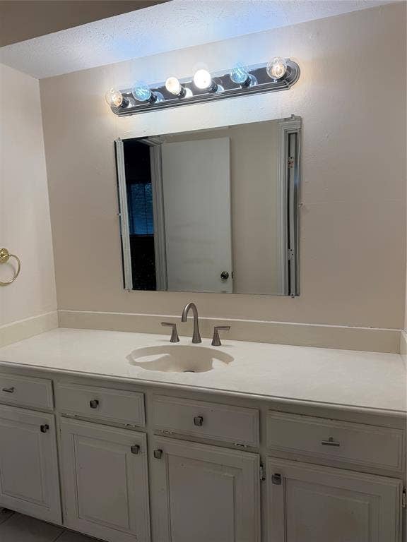 2408 Skiles Drive, Plano, TX 75075 Vanity with white cabinets, light-toned countertop, integrated sink, and brushed nickel faucet