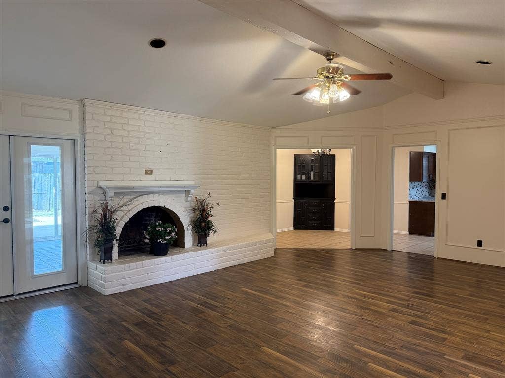 2408 Skiles Drive, Plano, TX 75075 Vaulted ceiling with exposed beam, white brick fireplace, wood-finish flooring, glass-paneled door, and ceiling fan