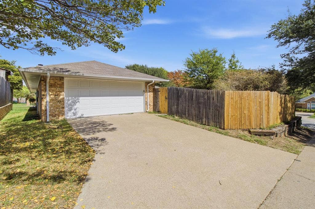 438 Blueridge Drive, Duncanville, TX 75137 Attached two-car garage with white sectional door, concrete driveway, and wood privacy fencing