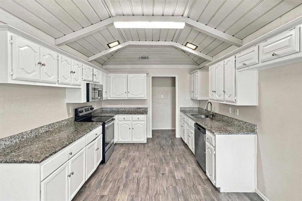 438 Blueridge Drive, Duncanville, TX 75137 Kitchen featuring white cabinetry, stone-finish countertops, wood-finish flooring, vaulted ceilings with exposed beams, and stainless steel appliances