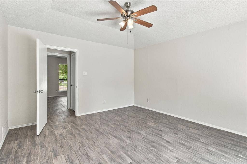 438 Blueridge Drive, Duncanville, TX 75137 Neutral-toned room featuring tray ceiling, wood-finish flooring, and ceiling fan with integrated lighting