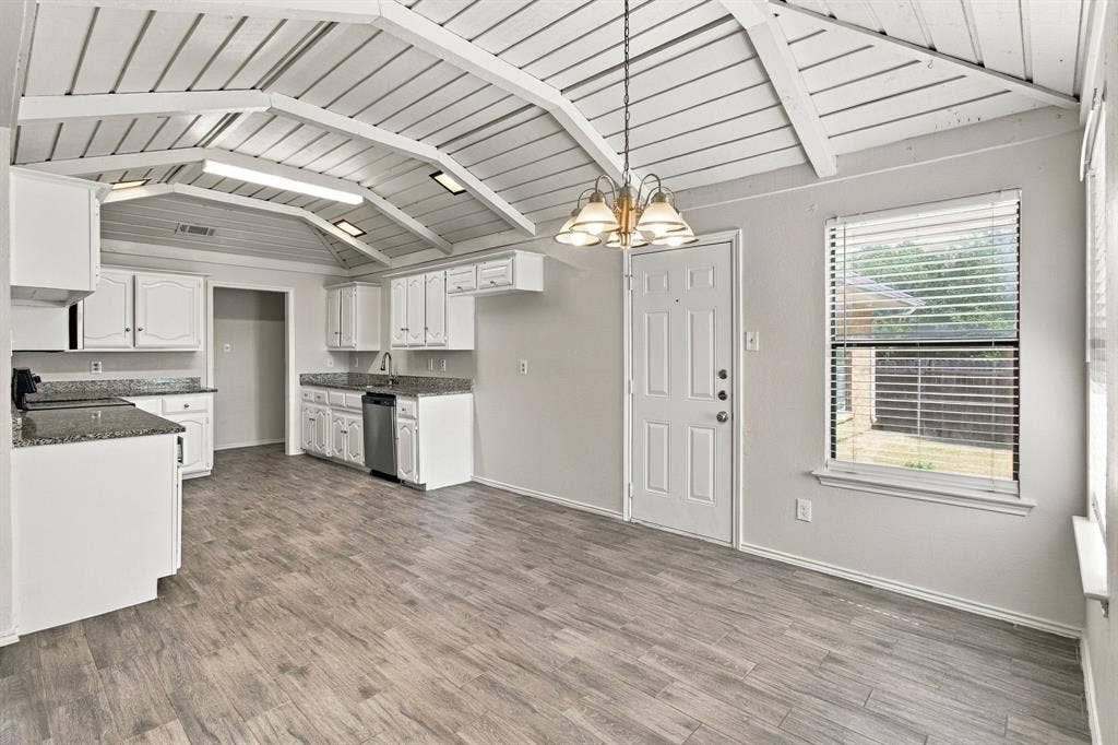 438 Blueridge Drive, Duncanville, TX 75137 Vaulted ceiling with exposed white beams, wood-finish flooring, white cabinetry, stone-finish countertops, and an integrated multi-bulb chandelier