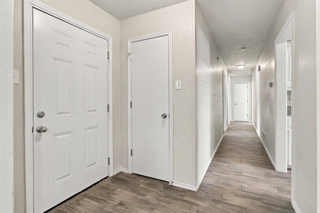 438 Blueridge Drive, Duncanville, TX 75137 Entryway featuring a six-panel exterior door, neutral wall finishes, and wood-finish flooring extending throughout the hallway