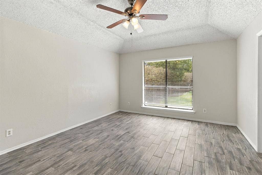 438 Blueridge Drive, Duncanville, TX 75137 Room featuring a tray ceiling, wood-finish tile flooring, a central ceiling fan with integrated lighting, and a single-pane window with horizontal blinds
