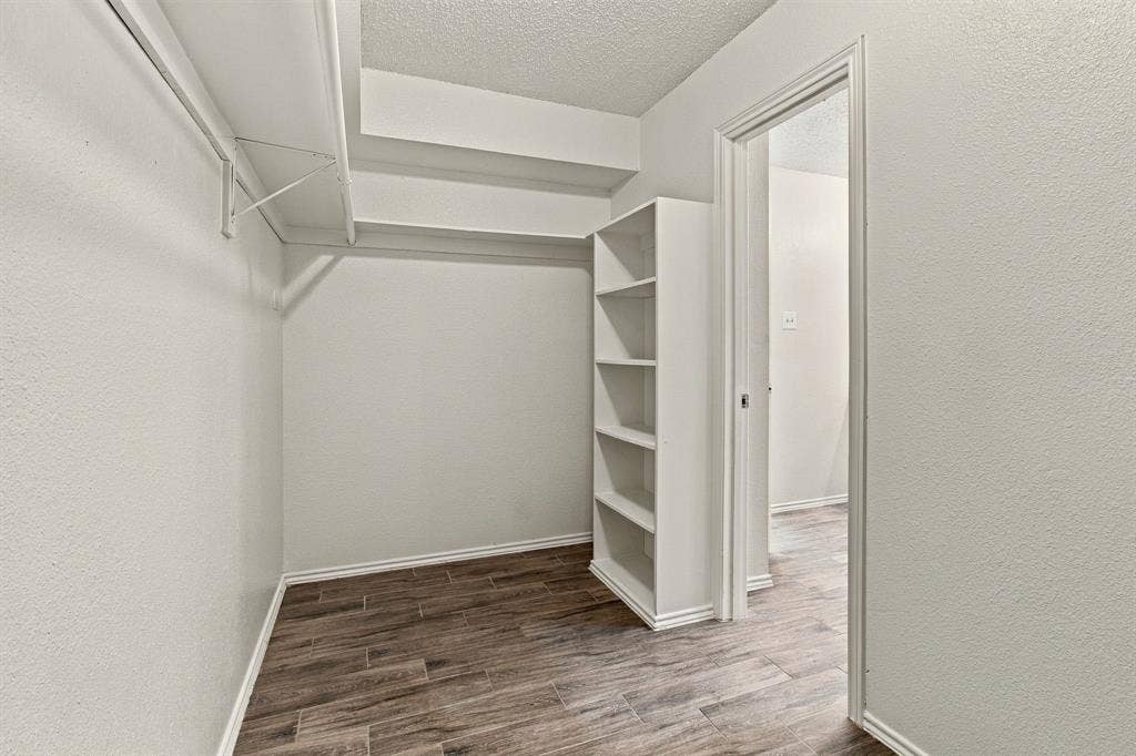 438 Blueridge Drive, Duncanville, TX 75137 Walk-in closet featuring wood-finish flooring, built-in shelving unit, and overhead shelving rods