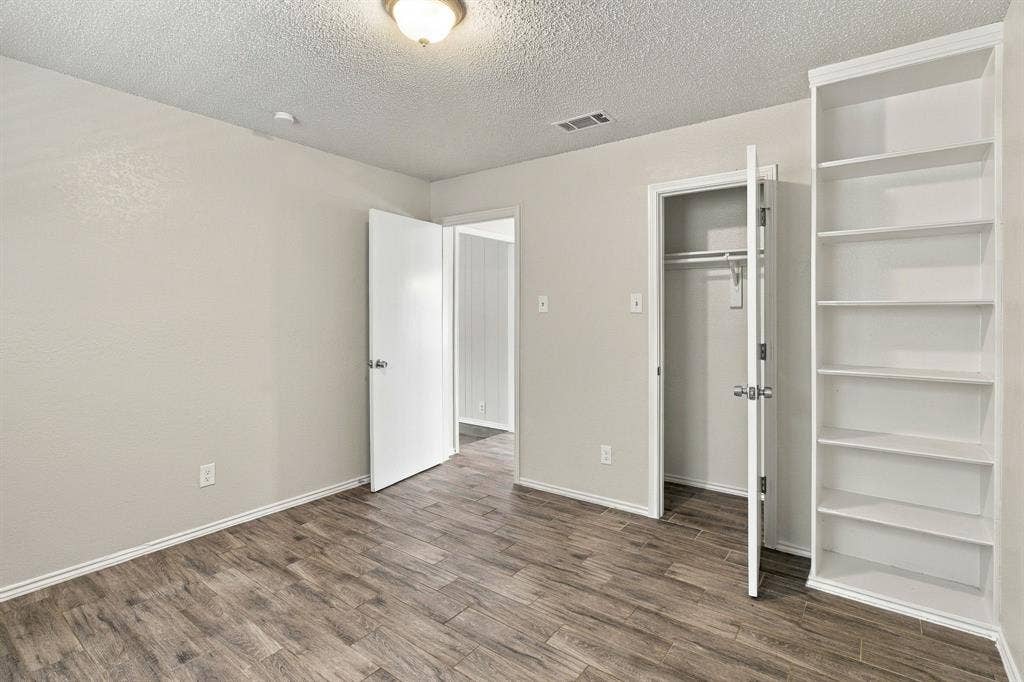 438 Blueridge Drive, Duncanville, TX 75137 Wood-finish flooring, built-in shelving, and neutral wall color