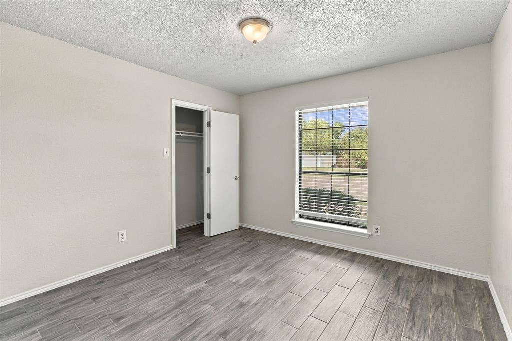 438 Blueridge Drive, Duncanville, TX 75137 Neutral-toned walls, wood-finish tile flooring, a walk-in closet with integrated shelving, and a dual-pane window with horizontal blinds