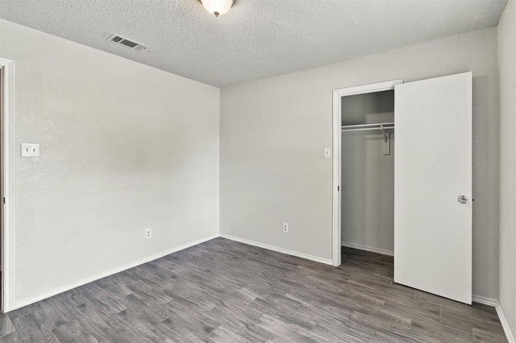438 Blueridge Drive, Duncanville, TX 75137 Interior room featuring wood-finish flooring, neutral wall paint, and a reach-in closet with an integrated rod
