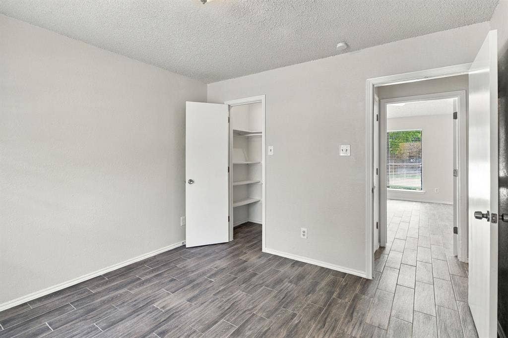 438 Blueridge Drive, Duncanville, TX 75137 Interior room featuring wood-finish tile flooring, neutral wall paint, and a built-in closet with integrated shelving