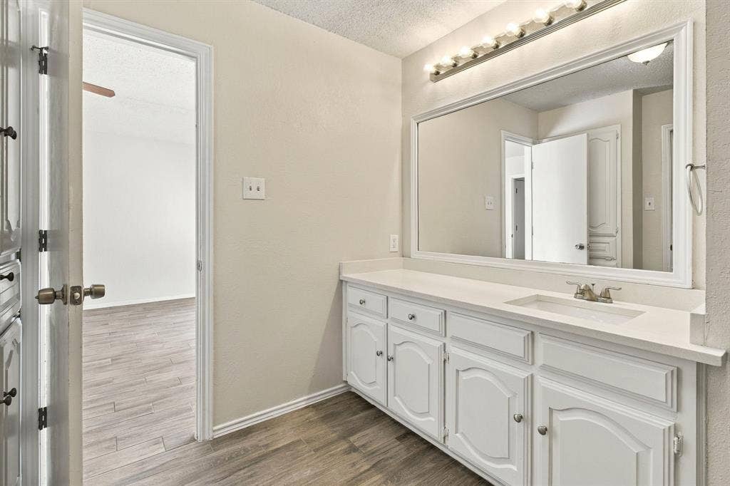 438 Blueridge Drive, Duncanville, TX 75137 Vanity featuring white built-in cabinetry, a wide countertop, a large framed mirror, and a multi-bulb light fixture