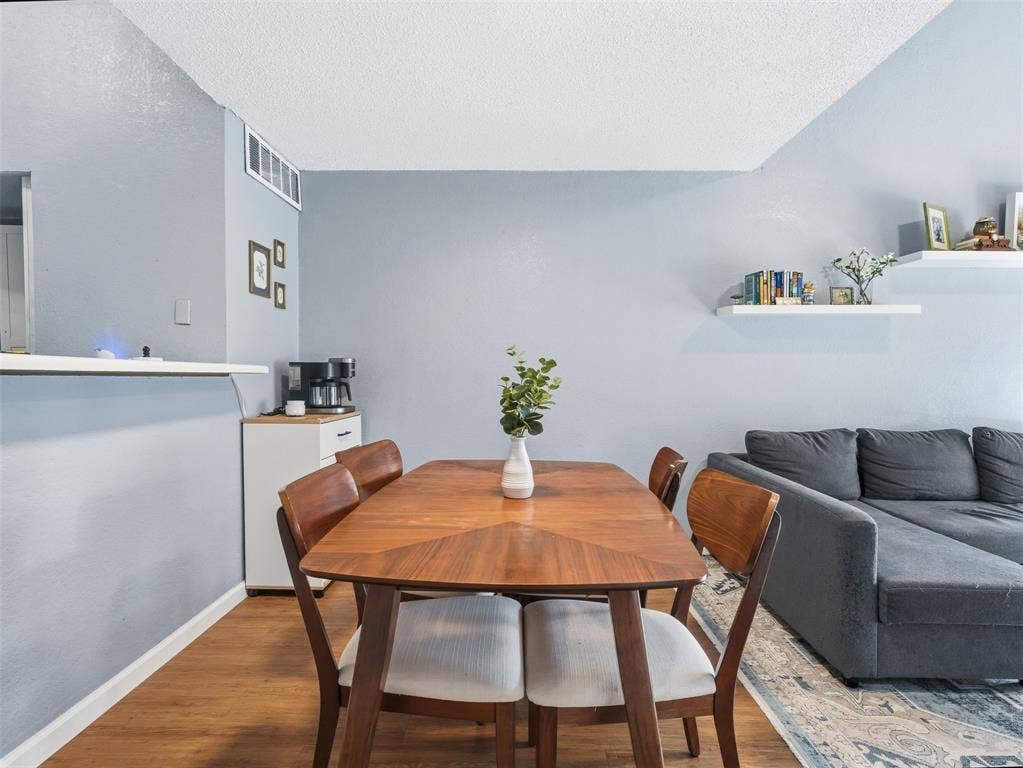 Wood-finish flooring, white wall-mounted shelving, and a breakfast bar counter