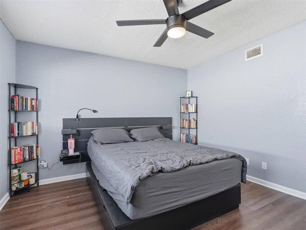 Wood-finish flooring, dark-finish ceiling fan with integrated lighting, and neutral-toned wall paint