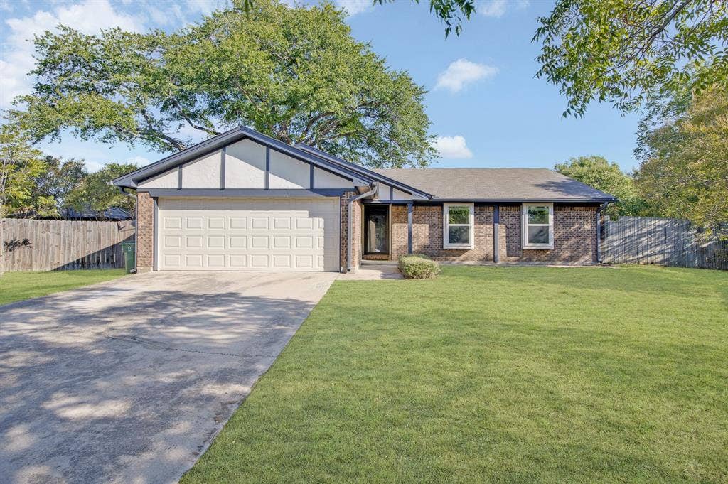 912 Shell Court, Bedford, TX 76022 Brick exterior with white trim details, an attached garage, a concrete driveway, and a fenced perimeter