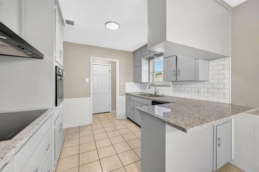 912 Shell Court, Bedford, TX 76022 Galley kitchen featuring light gray cabinetry, built-in oven, solid surface countertops, subway tile backsplash, and tile flooring