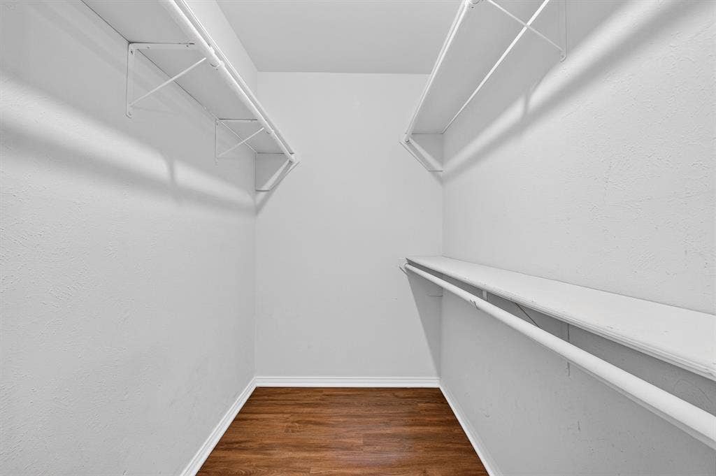 912 Shell Court, Bedford, TX 76022 Walk-in closet featuring wood-finish flooring, white walls, and built-in shelving with hanging rods