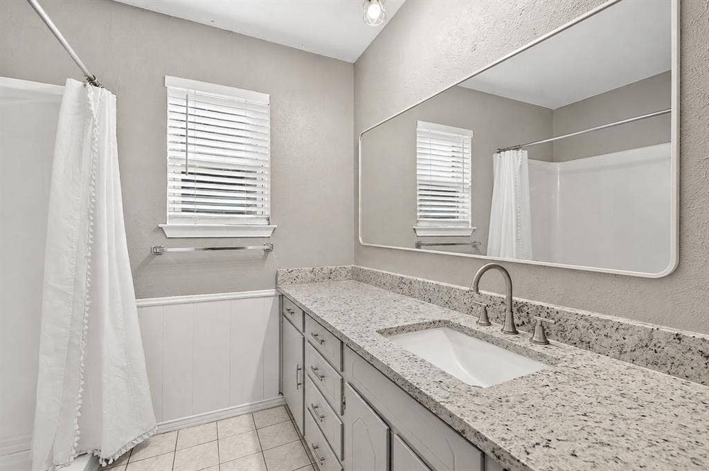 912 Shell Court, Bedford, TX 76022 Double vanity with a rectangular undermount sink, speckled countertop, and brushed nickel faucet