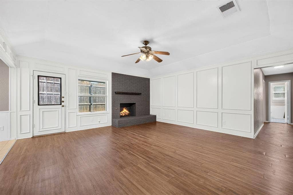 912 Shell Court, Bedford, TX 76022 Wood-finish flooring, white paneling, brick fireplace with mantel, ceiling fan, and a glass-paned door