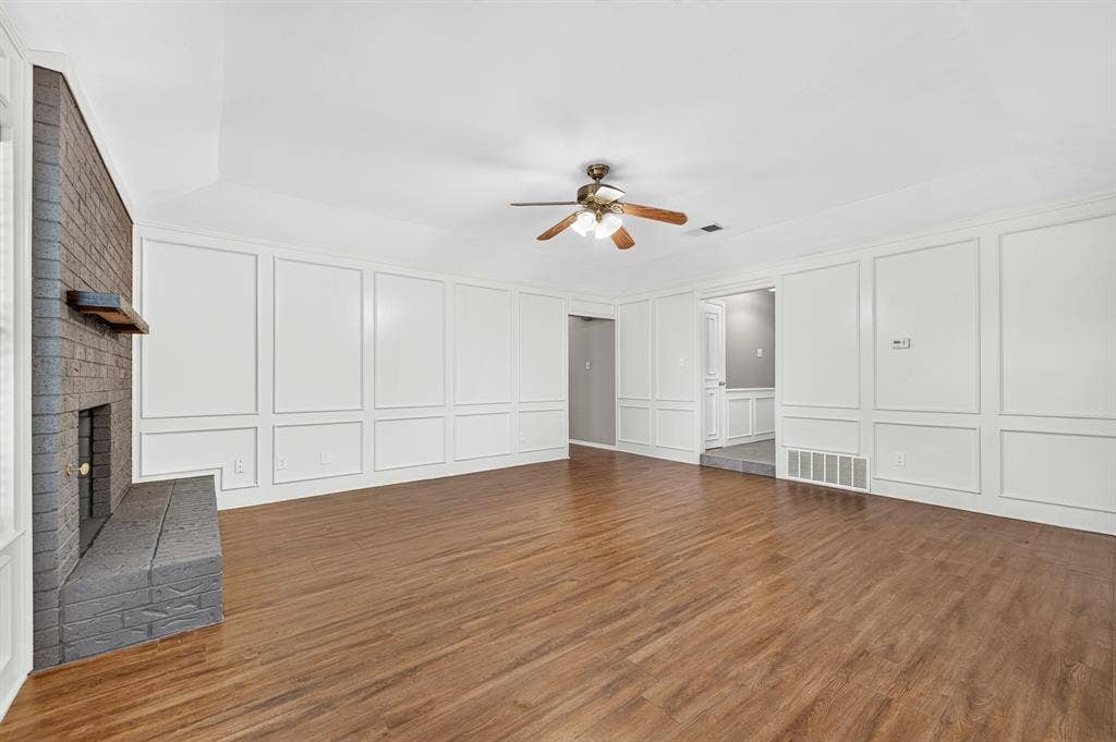 912 Shell Court, Bedford, TX 76022 Spacious room with wood-finish flooring, a brick fireplace, and extensive wall paneling