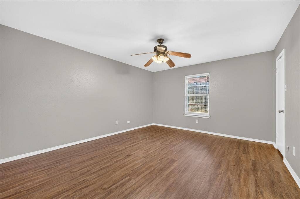 912 Shell Court, Bedford, TX 76022 Spacious room featuring wood-finish flooring, light gray walls, a ceiling fan with integrated lighting, and a window for natural illumination